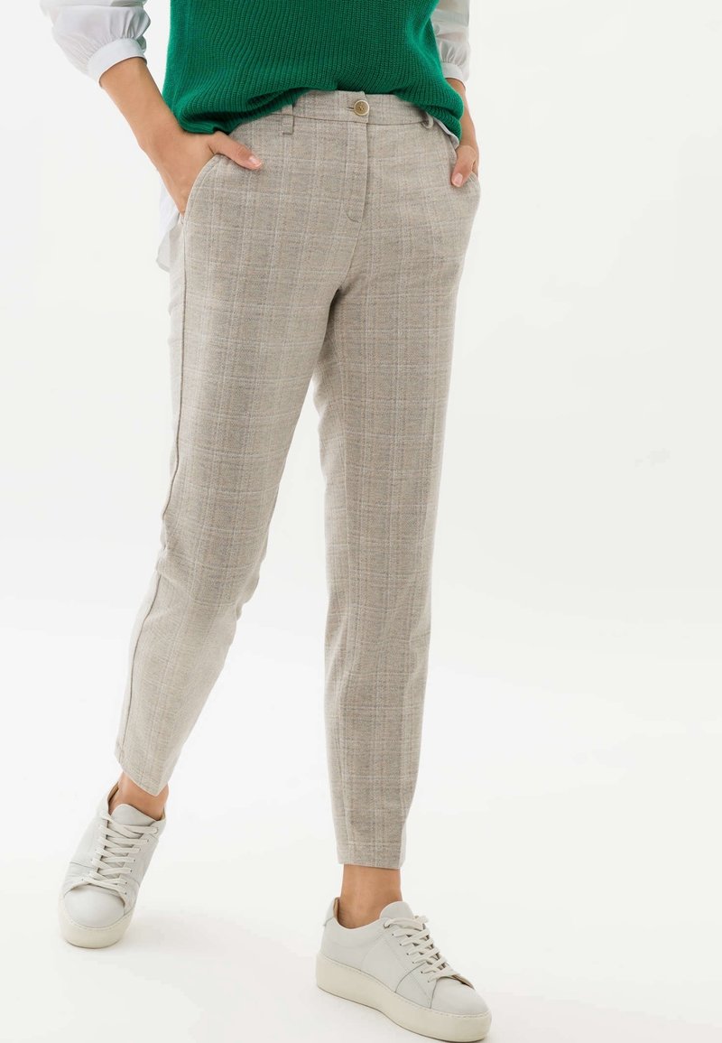 Pantalon à carreaux gris clair avec une coupe ajustée, poches latérales et une texture lisse, associé à des baskets blanches.