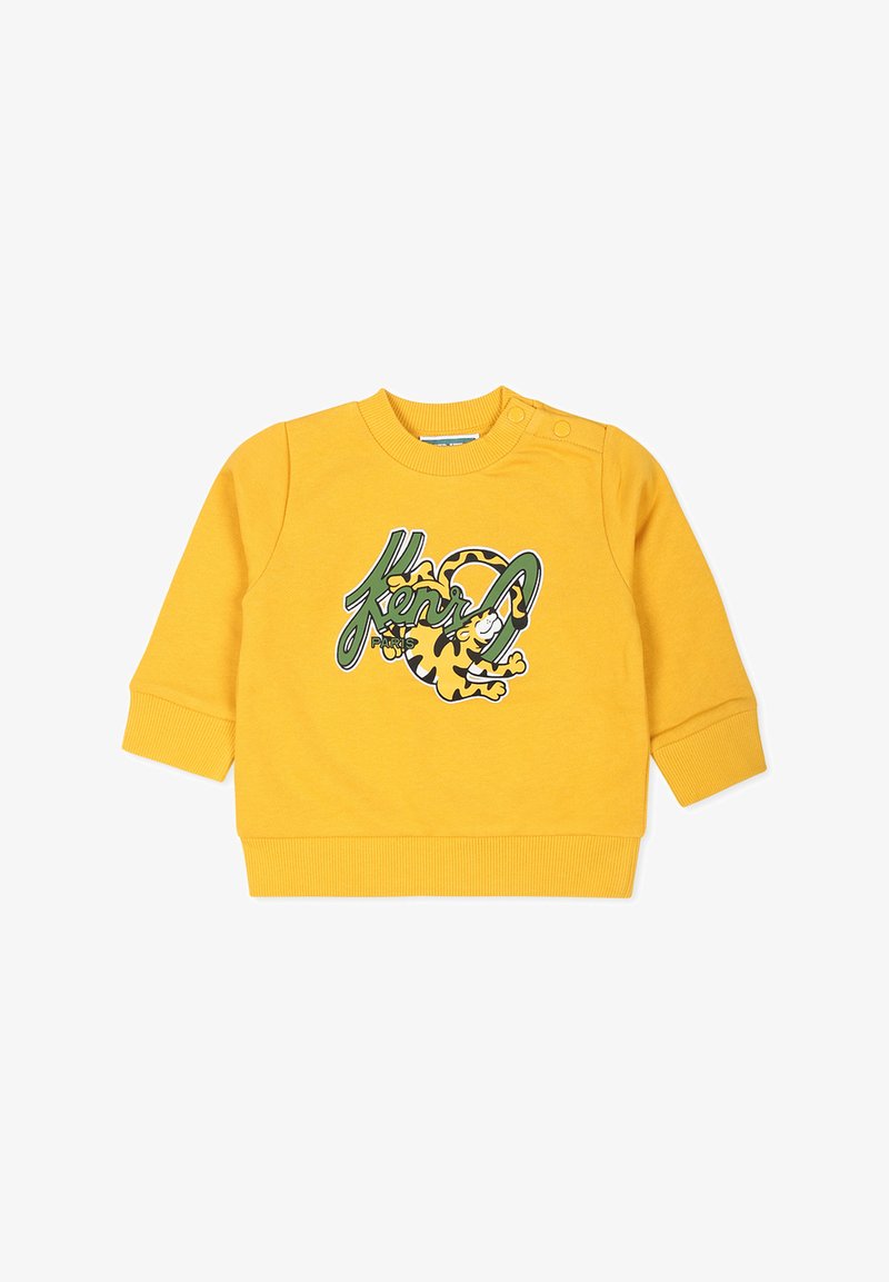 Sweatshirt jaune à manches longues, avec des poignets côtelés et un col rond. Présente un graphique ludique avec un tigre et un motif de texte. Texture lisse.