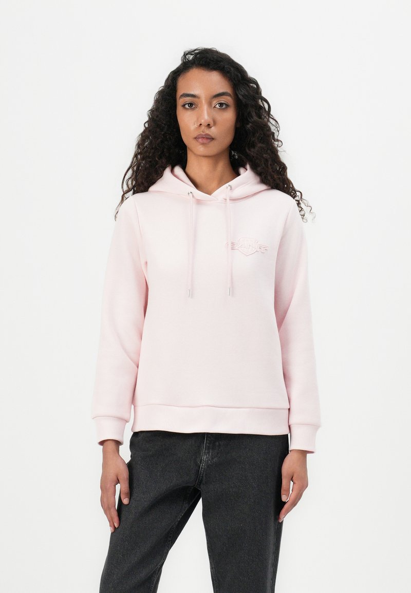Sudadera de color rosa claro con un bolsillo frontal, capucha con cordones y logo bordado. Presenta mangas largas y un dobladillo acanalado, fabricada con un tejido suave.