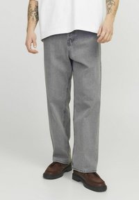 Gray denim jeans with a loose fit, straight legs, and a faded texture, paired with dark brown shoes featuring a textured sole.