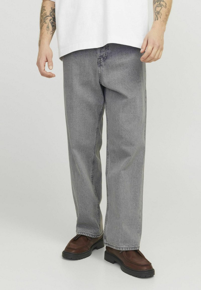 Gray denim jeans with a loose fit, straight legs, and a faded texture, paired with dark brown shoes featuring a textured sole.