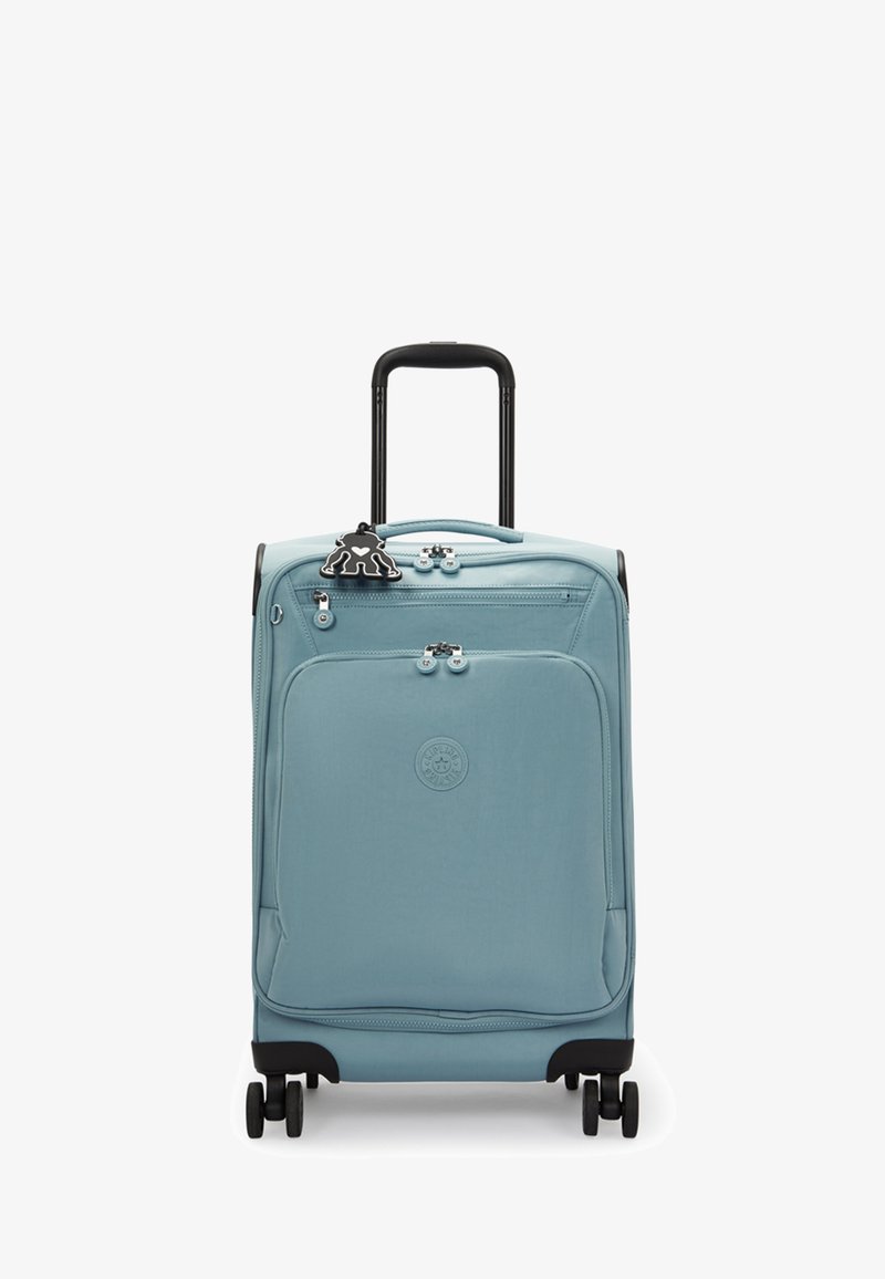 Valise souple bleue avec une poignée rétractable noire, quatre roues et une poche avant. Présente une étiquette décorative noire.