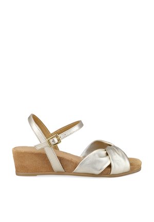 Sandalia de cuña plateada con tiras delanteras cruzadas, hebilla ajustable en el tobillo y tacón de cuña de ante tostado.