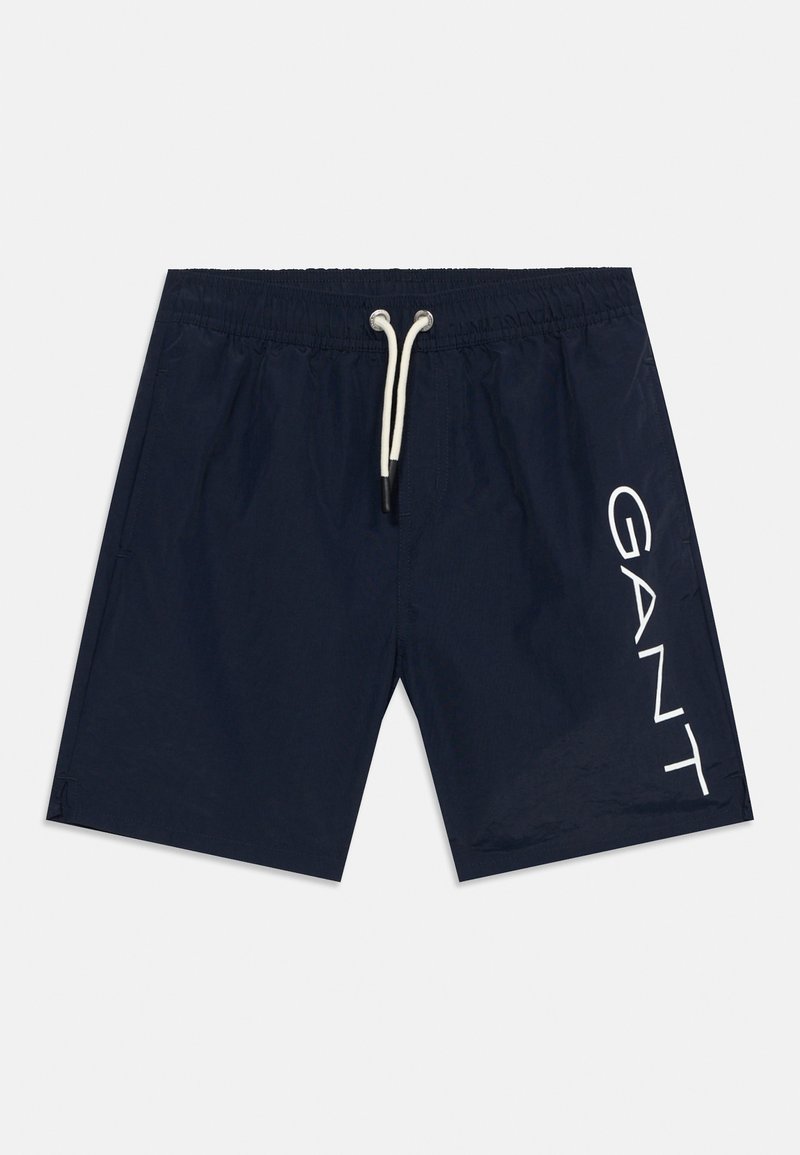 Μπλε σκούρο μαγιό σορτς με λευκό κορδόνι στη μέση και μεγάλο λευκό λογότυπο «GANT» τυπωμένο κάθετα στο αριστερό πόδι.