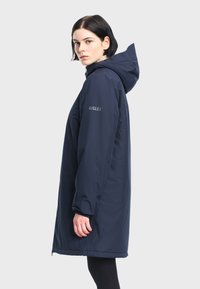 Marineblauwe, lichte waterdichte parka met capuchon, lange mouwen en een ritssluiting. Inclusief logo op de mouw en een comfortabele pasvorm.