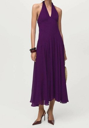 Femme portant une robe midi violette sans manches à col halter avec des plis, des talons hauts bordeaux et des bracelets noirs et bordeaux à un poignet.