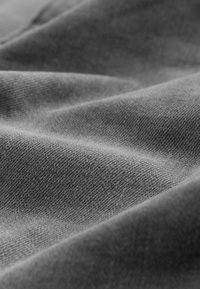 Grijze stof met een gladde textuur, met subtiele diagonale wevingen en zachte dracht, waardoor er zachte plooien en schaduwen ontstaan.