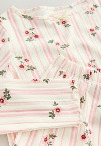 Cotton pajama set with pink and white stripes. Features small floral patterns and ruffled edges on sleeves and waistband. Soft texture.