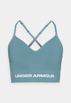 Teal športni nedrček z gladko teksturo, nastavljivimi X-zapenjanimi naramnicami in belim napisom "UNDER ARMOUR" ob robu.