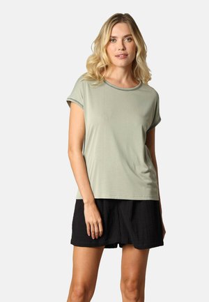 T-shirt vert clair à manches courtes avec un col rond et une bordure discrète, associé à un short noir ample. Texture lisse et coupe décontractée.