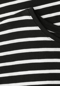 Gros plan sur un tissu rayé horizontal noir et blanc avec un détail de couture en forme de V au niveau de l'encolure.