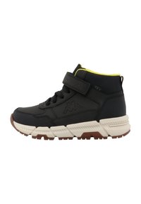 Zapatilla alta negra con parte superior texturizada, correa de velcro ajustable y acentos vibrantes en amarillo. Suela gruesa blanca y marrón.