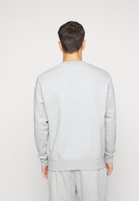 Sudadera gris hecha de un tejido suave, con cuello redondo y puños acanalados. Tiene un corte holgado y costuras mínimas para mayor comodidad.