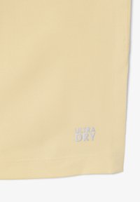Tessuto giallo chiaro con orlo cucito e logo con testo "ULTRA DRY" ricamato in bianco vicino al bordo inferiore.