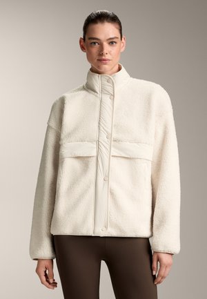 Crème-kleurige fleece jas met een hoge kraag, drukknoopsluiting en een gladde voorkant. Beschikt over een zachte, pluizige textuur.