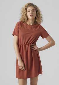 Robe à manches courtes de couleur rouille avec un corsage en texture et une taille élastique, offrant une coupe détendue avec une jupe évasée.