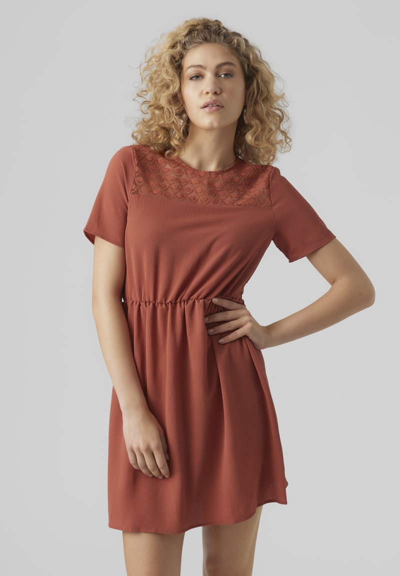 Robe à manches courtes de couleur rouille avec un corsage en texture et une taille élastique, offrant une coupe détendue avec une jupe évasée.