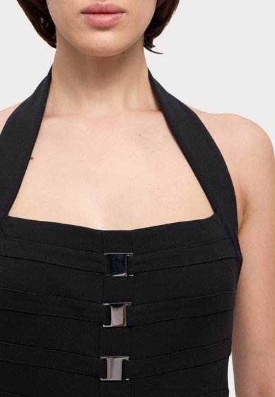 Rochie neagră cu guler halter, având panouri orizontale și trei accente metalice în față, cu o textură netedă și o croială ajustată.