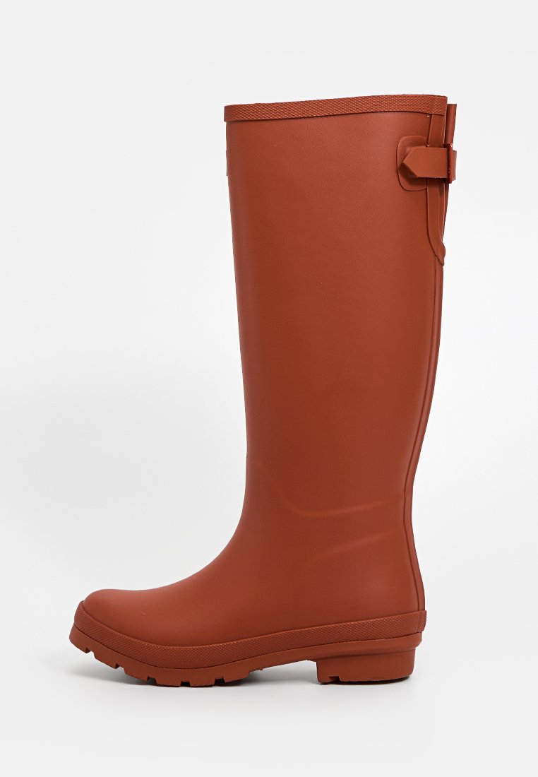 Botas de goma marrones, impermeables, hasta la rodilla, con suela texturada y detalle de correa en el lateral. Exterior suave, forma ergonómica para mayor comodidad.