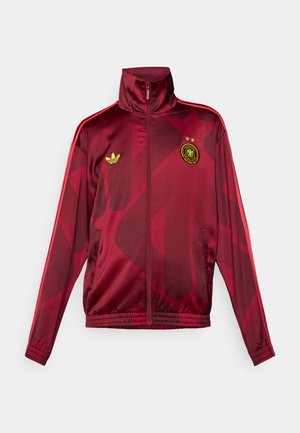 Red track jacket with a high collar, featuring a geometric pattern, green Adidas logo, and an emblem with two stars on the chest.
