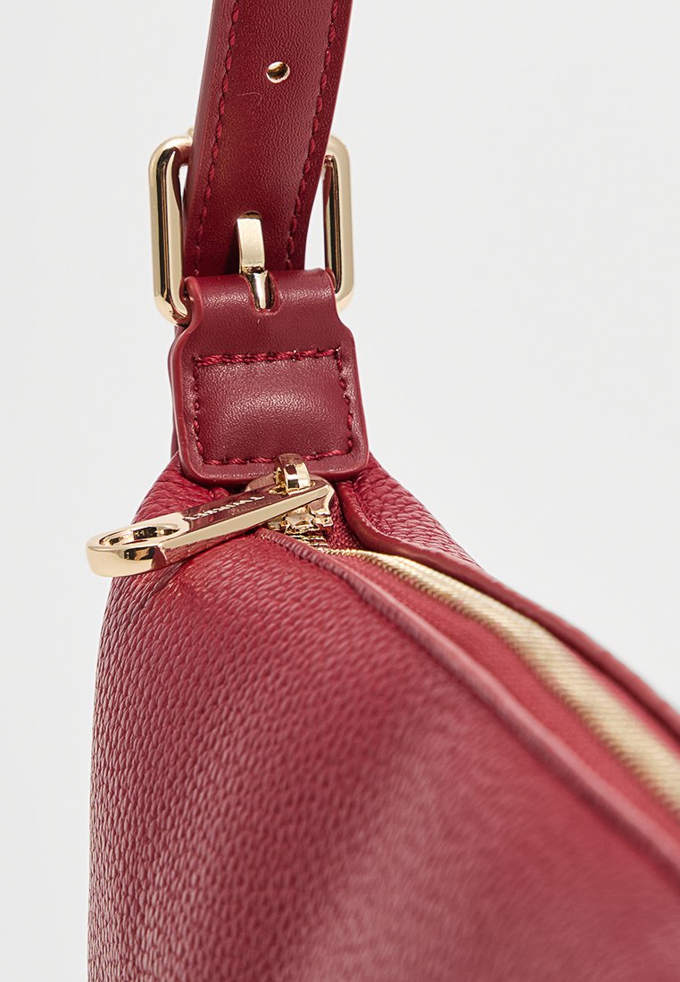 Borsa in pelle rossa testurizzata con zip e accessori dorati. Include un attacco per una tracolla robusta e un dettaglio di apertura con zip liscia.