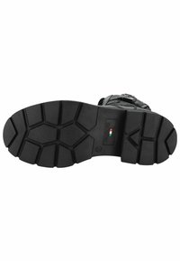Semelle de botte noire présentant un motif de bande de roulement robuste avec de profonds sillons, en caoutchouc. Comprend un détail du logo de la marque sur le côté.
