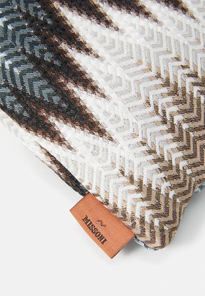 Textured cushion featuring a chevron pattern in shades of brown, gray, and white with a tan label showing "Missoni" sewn into the side.