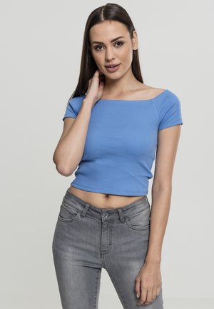 Sininen ribattu crop top, jossa on neliökaula-aukko ja lyhyet hihat, yhdistettynä korkeavyötäröisiin harmaisiin farkkuihin. Sujuva rakenne, istuva muotoilu.