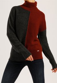 Strickpullover mit Rollkragen, der ein Farbblockdesign in Dunkelgrau und Rost zeigt, gerippte Bündchen und Saum hat und mit einem kleinen silbernen Akzent-Tag versehen ist.