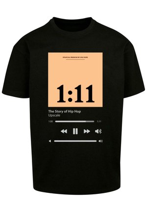 Mustat puuvillapaidat, joissa on graafinen muotoilu persikkataustalla, suuri musta teksti, joka näyttää "1:11" ja toistokontrollit.