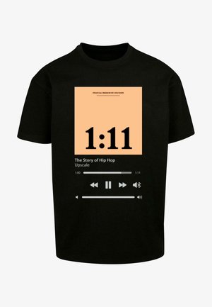Czarny bawełniany t-shirt z graficznym wzorem na brzoskwiniowym tle, z dużym czarnym napisem "1:11" oraz przyciskami odtwarzania.