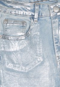 Ljusblå metalliska jeans med en glansig finish, som har en framlapp, bälteshällor och en metallknappsstängning. Texturerad yta synlig.