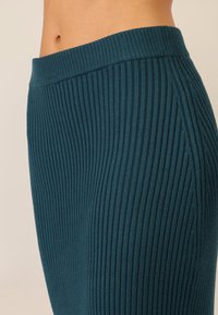 Ribbed teal spódnica z szerokim pasem, z pionowymi liniami i teksturowaną powierzchnią. Widoczne szwy boczne.