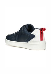 Zapatilla azul marino con parte superior de cuero liso, suela de goma blanca y una lengüeta en el talón a rayas rojas y blancas para un detalle adicional.