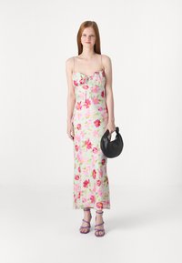 Φλοράλ μάξι φορεμα με τιράντες spaghetti, σε ροζ και πράσινες αποχρώσεις, με σGathered bust και πλάγιο σκίσιμο; συνδυάζεται με μια μαύρη τσάντα και μοβ ψηλοτάκουνα.