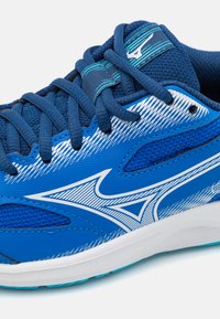 Chaussure de sport bleue avec des sections en maille, des accents blancs, des lacets texturés et un design incurvé arborant un logo de marque distinct.