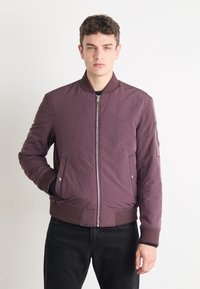 Maroon bomber jacket with a zip front, side pockets, and ribbed cuffs. Smooth fabric with a classic design. Suitable for casual wear.