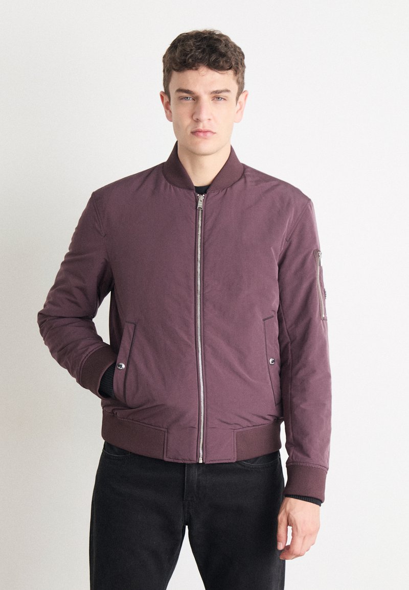 Maroon bomber jacket with a zip front, side pockets, and ribbed cuffs. Smooth fabric with a classic design. Suitable for casual wear.