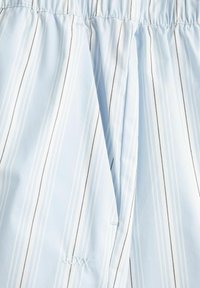 Šviesiai mėlynas dryžuotas audinys su vertikaliomis baltomis ir tamsiai pilkomis juostomis. Elastingas juosmuo su siuvinėtu ornamentu apdailoje. Minkšta tekstūra.