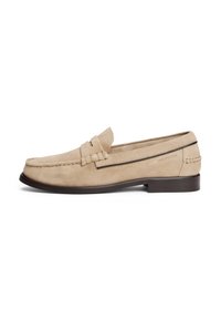 Beige semskede mokkasiner med en sydd design, en detalj med frontbånd, og en mørk brun såle. Har "HILFIGER"-logoet preget på siden.
