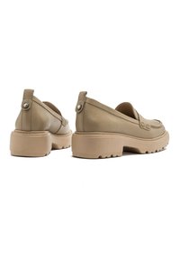 Beżowe skórzane mokasyny z niskim, masywnym obcasem i okrągłym noskiem, z subtelnymi detalami przeszycia i teksturowanym wykończeniem.