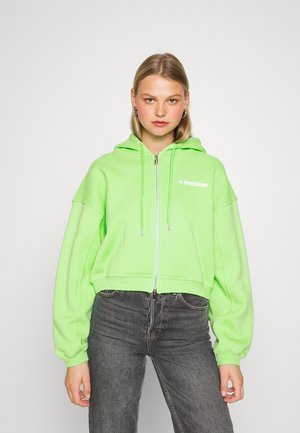 Sweatshirt com capuz cortado em verde neon brilhante, com fecho frontal de zíper e mangas oversized. Logotipo da marca impresso em branco.