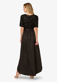 Czarna wieczorowa suknia z cekinowym gorsetem, krótkimi rękawami i zwiewną satynową spódnicą z talią wciętą oraz długim dołem.