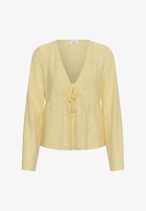 Blusa de manga larga color amarillo pálido con escote en V, textura floral sutil y cierre de lazo frontal.