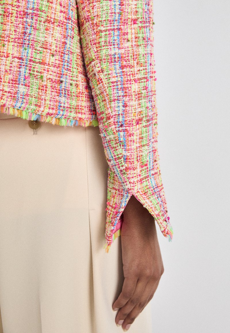 Farbenfrohe Tweed-Jacke mit einem strukturierten Muster in Pink, Grün und Blau. Verfügt über einen fransigen Saum und einen Schlitz an den Ärmelabschlüssen.