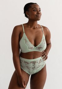 Lichtgroene kant bralette met een diepe V-hals en verstelbare bandjes, gecombineerd met bijpassende hoge taille briefs van kant, met bloemmotieven.