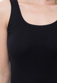 Black tank top with a rounded neckline. Made of soft, stretchy cotton material. Features narrow straps and a fitted design.
