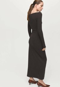Donkergrijze, nauwsluitende jurk met lange mouwen, gemaakt van zachte stof, met een boothals en een rechte silhouet die tot aan de enkels reikt.