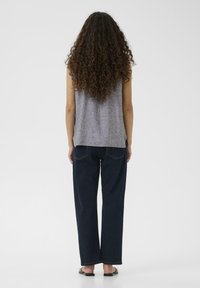 Hallharjaga ilma varrukat särk, millel on tekstuuriline viimistlus, koos tumesiniste laienevate teksadega, millel on nähtavad õmblused ja tagataskud.