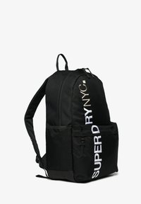 Czarny plecak o teksturowanym wykończeniu, z dużą kieszenią z przodu i białym napisem "SUPERDRY NYC" w metalicznych akcentach.